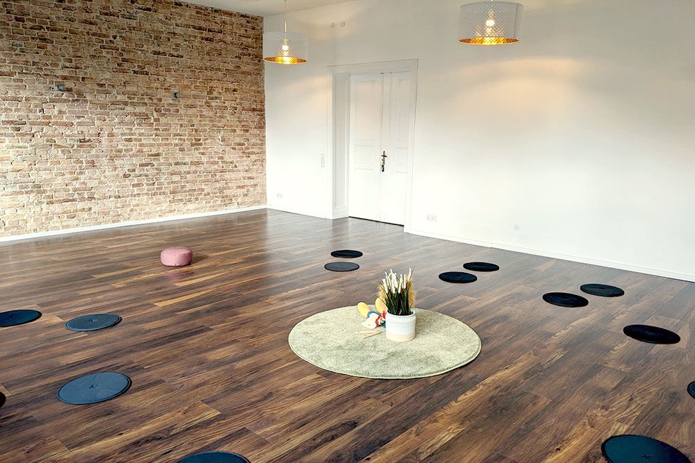 Foto vom großen Raum mit runden Matten und Yogakissen